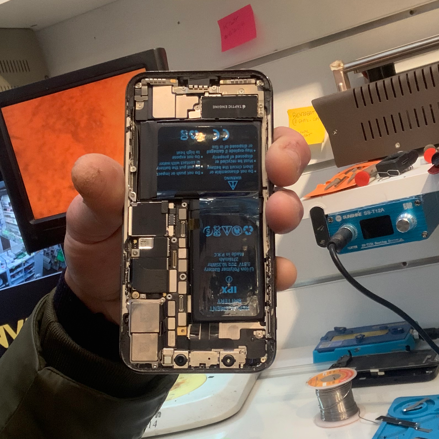 iPhone ouvert dans l’atelier SOS PHONE, avec sa batterie visible