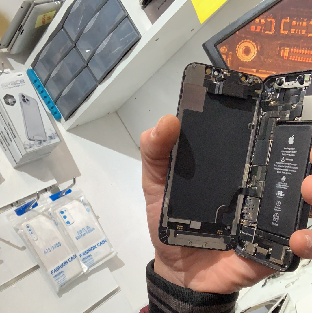 iPhone ouvert tenu sur le poste de réparation dans l’atelier SOS PHONE